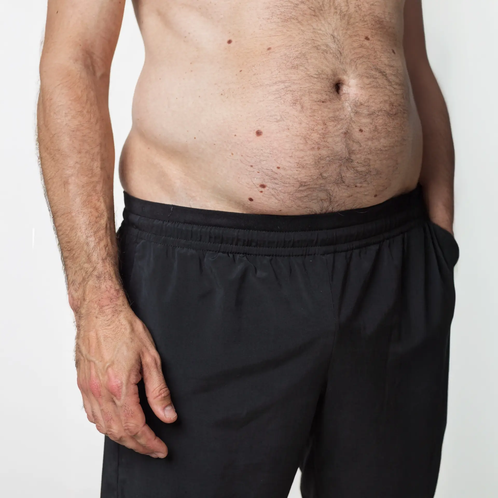 AI-generated close view of a character's midsection and hand beside black shorts